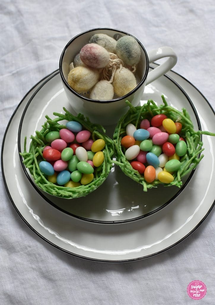 Essbares Osternest mit Baisereiern gefüllt auf einem Teller mit Schale