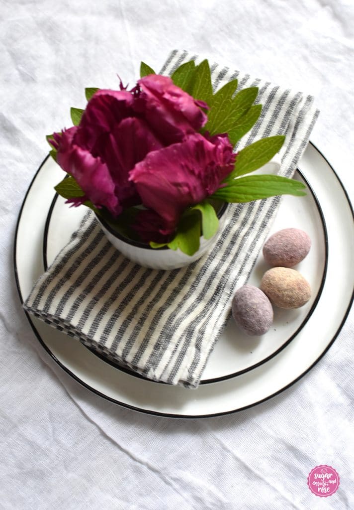 Teller und Schale mit Serviette, drei Lindt Fruchteiern und einer Schale mit einer weinroten gefierderten Tulpe