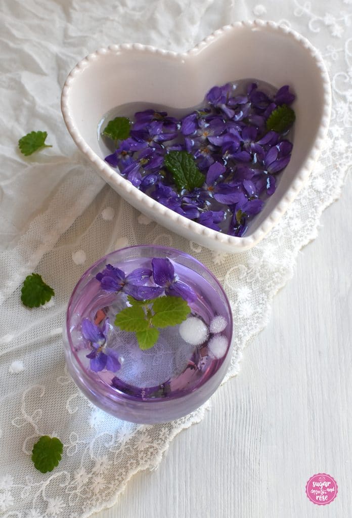Veilchenwasser in Glas und Schale mit Veilchenblüten