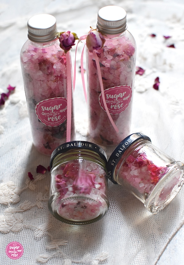 Rosenbadesalz abgefüllt in kleinen Fläschchen  mit Sugar&Rose-Etikett und rosa Schleife und zwei kleine Gläschen mit Schraubverschluss