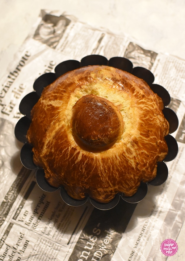 In Sepiabrauntönen eine alte Zeitung, darauf eine original blütenförmige, schwarze Metallbriocheform mit Kopfbrioche