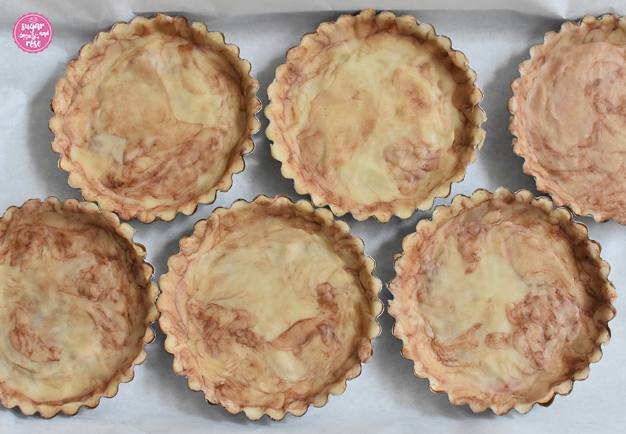 Mit Kakao marmorierter Mürbteig in sechs Tarteletteförmchen auf weißem Tuch