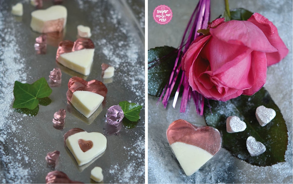 Links ein Silbertablett mit zweifarbigen Jellyherzen (halb milchig weiß, halb durchsichtig rosa); rechts eine rosa Rose, davor ein großes Jellyherz und drei kleine in Silberflitter getauchte Jellyherzen