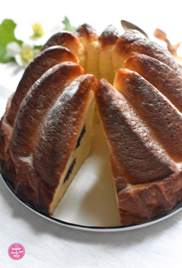 Großaufnahme des angeschnittenen Topfenmohngugelhupfs auf einem weißen Porzeallanteller mit dunkelblauem Rand