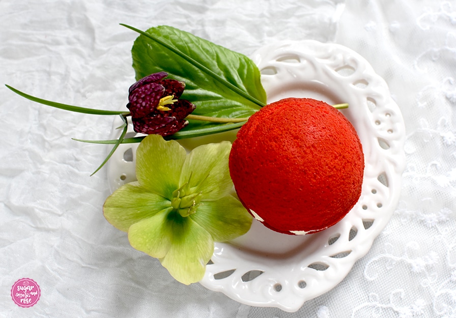 Ein herzförmiger weißer Keramikteller mit einem Whoopie und Blüten von der Schneerose und eine weinrote Schachbrettblume