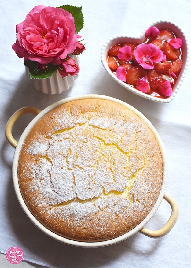 Grießauflauf in gelber Riess-Emailpfanne mit Erdbeer-Geranien-Kompott in herzförmiger Keramikschale, daneben eine kleine Vase mit einer pinkfarbenen Rosenblüte (Rosarium Uetersen)