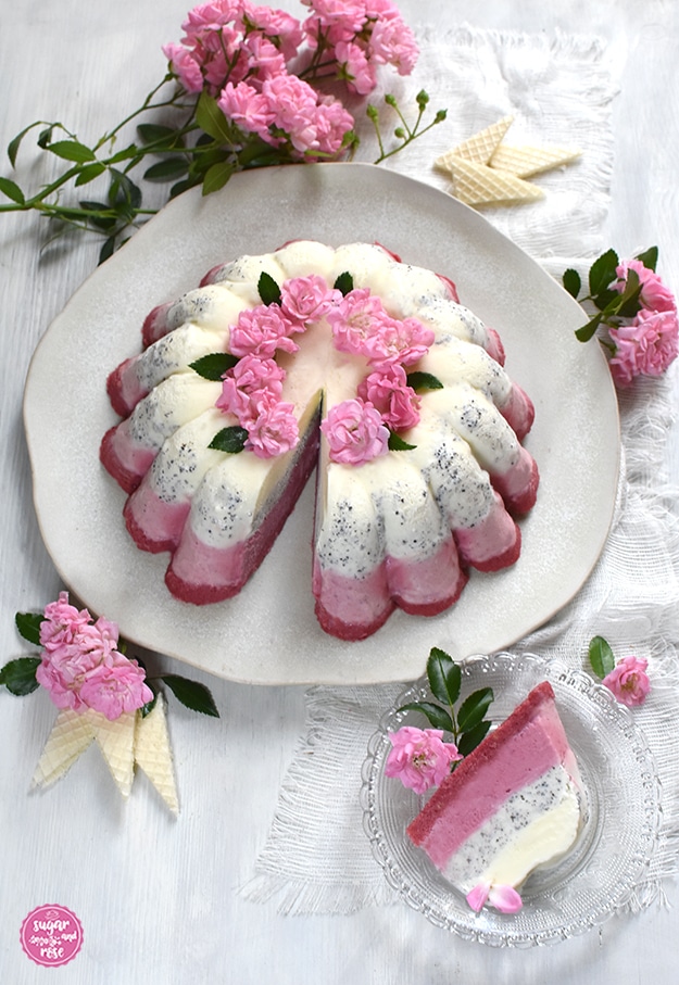 Angeschnittener Eisgugelhupf, rundum dekoriert mit Röschen und Eiswaffeln. Im Vordergrund ein kleiner Kristallglateller mit einem Stück vom Eis.