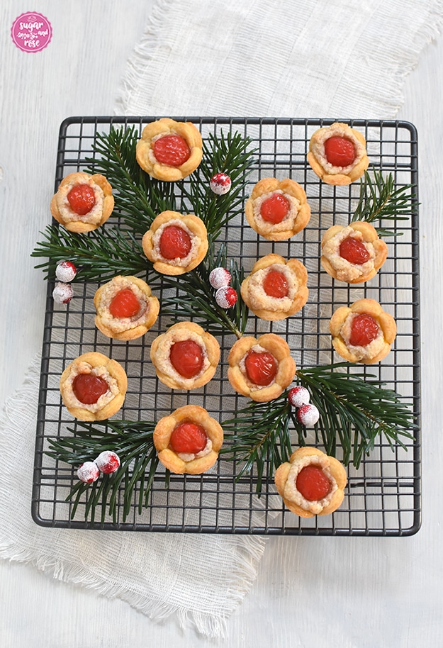 Christrosen-Kekse auf einem dunklen quadratischen Gitterrost mit Tannenzweigen und roten Früchten dekoriert