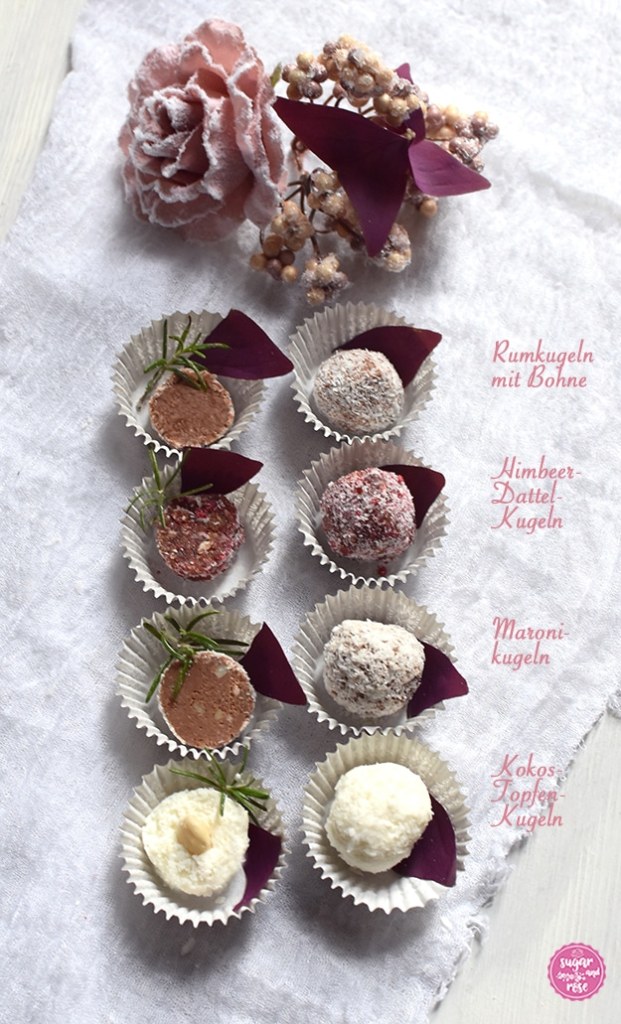 Vier Sorten Energiekugeln in weißen Papierschalen