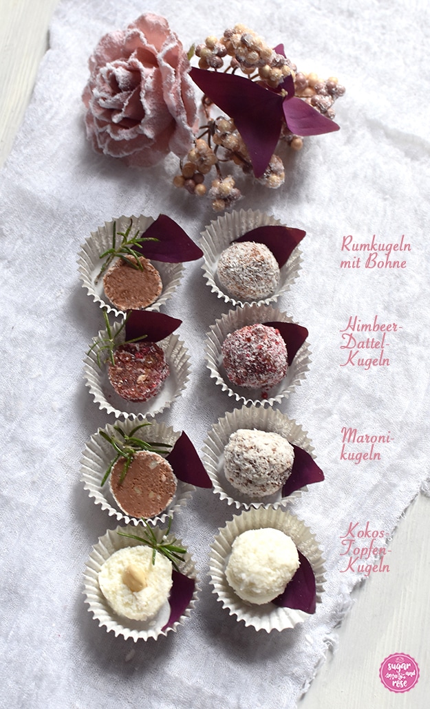 Die vier weihnachtlichen Energiekugeln in Papiermanschetten, einmal ganz, einmal in der Mitte aufgeschnitten, dekoriert mit weinroten Kleeblättern