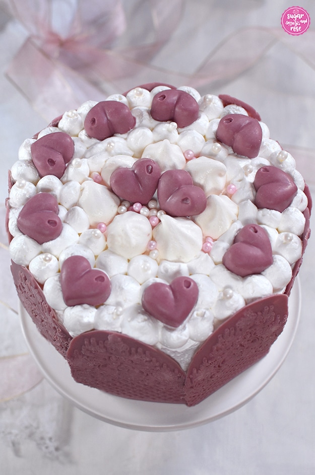 Ruby-Schokoladen-Torte auf weißer Etagere, dekoriert mit Ruby-Chocolate-Herzen und weißen Baisertuffs