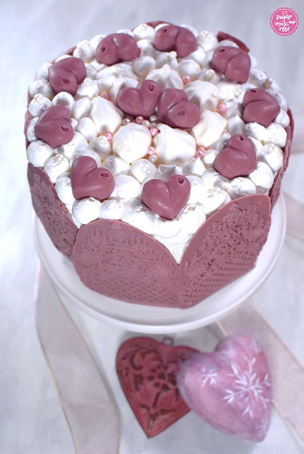 Ruby-Schokoladen-Torte auf weißer Etagere, davor zwei Herzen aus Keramik in Rosa und zartrosa Seidenbänder