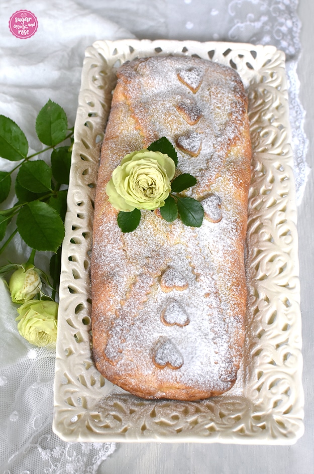 Apfelschlangerl (mürber Apfelstrudel) auf Keramiktablett, dekoriert mit grüner Rose