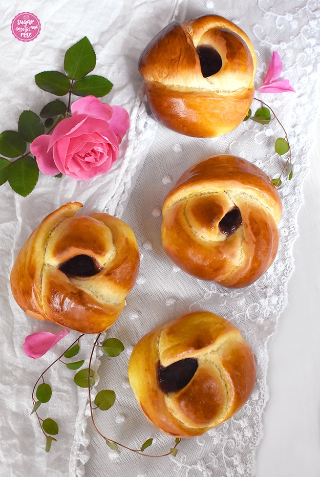 Vier Rosenbuchteln von oben fotgrafiert mit sichtbarem dunkelroten Marmealdeauge, daneben eine rosa Rose und einzelne rosa Rosenblüten