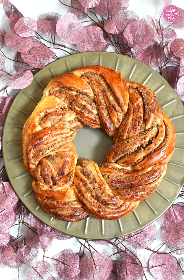 Hefe-Nusskranz auf messingfarbenen runden Metallteller, darunter rosefarbene Blättergirlande