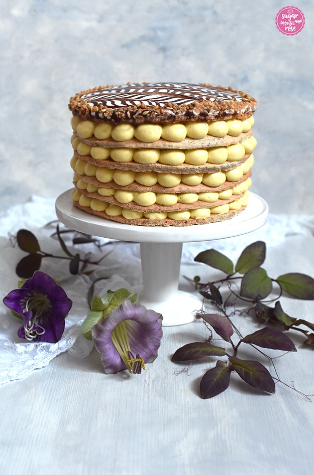 Esterházy-Torte auf Etagere. Sichbar sind die sechs Nussböden, dazwischen liegt die eigelbe Buttercreme, jede Schicht tupfenförmig aufgetragen