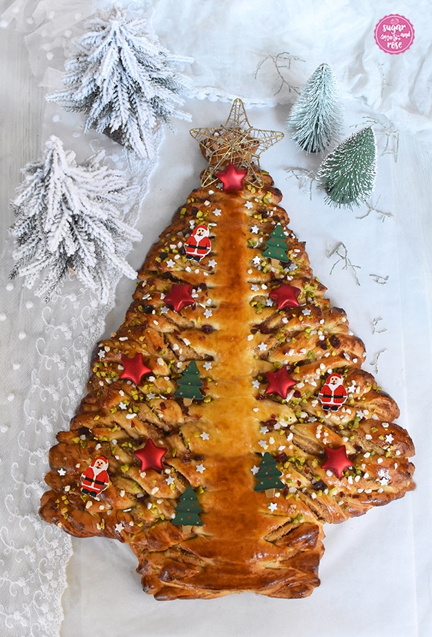 Hefe-Weihnachtsbaum mit Nussfüllung auf weißem Hintergrund, dekoriert mit goldener Sternspitze, kleine roten Sternen, Weihnachtsmännern und grünen Tannenbäumchen