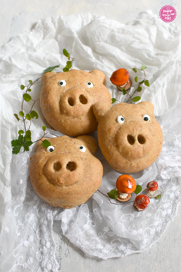 Drei Glücksschweinderl-Brötchen auf weißem Spitzentuch, im Vordergrund drei und im Hintergrund ein oranger Fliegenpilz aus Keramik