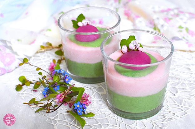 Matcha-Sakura-Dessert mit Grieß im Glas, unten eine grüne Matcha-Schicht, darüber eine rosa Schicht, ein Klacks Matchabrei und eine pinke Mochi und Kirschblüten obenauf