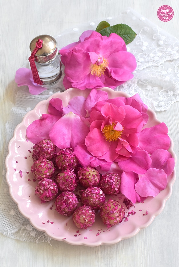 Rosenmarzipan auf rosa Keramikteller, dekoriert mit rosa Rosenblüten und einem arabischen Glasfläschchen mit Silberdeckel, gefüllt mit Rosenwasser