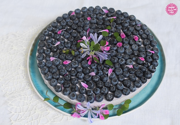 Heidelbeer-Cheesecake, dicht belegt mit Heidelbeeren und rosa Geranenblüten