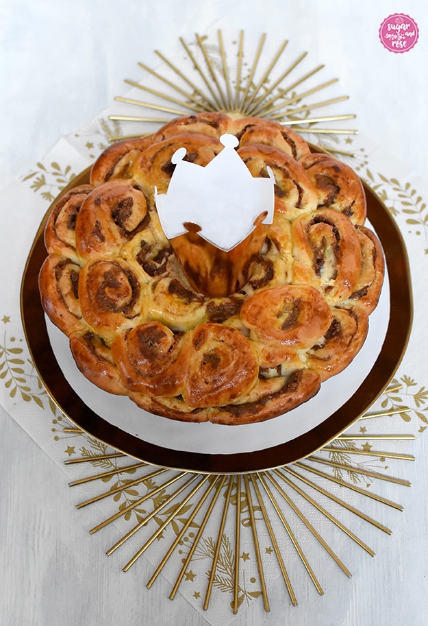 Dreikönigskuchen mit Kletzen auf Goldrandteller, in der Kuchenmitte eine goldene Papierkrone