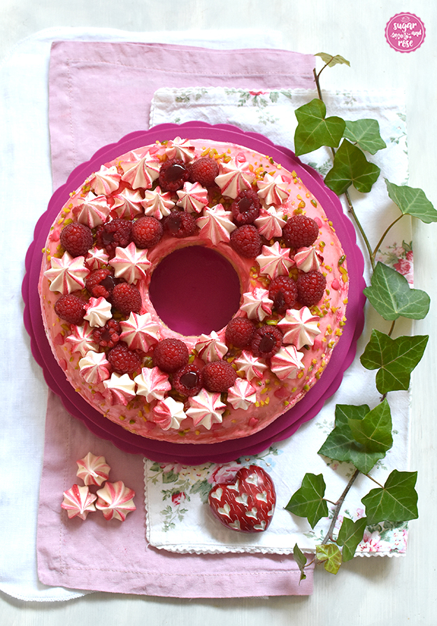 Himbeer-Pistazien-Saturntorte auf pinkem Tortenteller und dreierlei Leinenservietten in weiß, rosa, und geblümt, dazu eine Efeuranke und rotes Steinherz