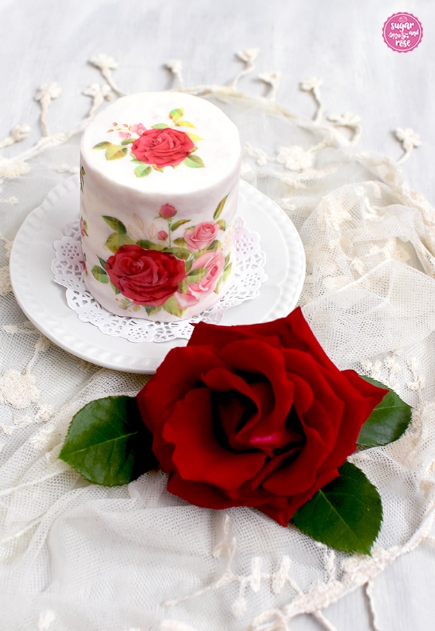 Rosentörtchen auf weißem Keramikdessertteller, davor eine rote Santana-Rosenblüte