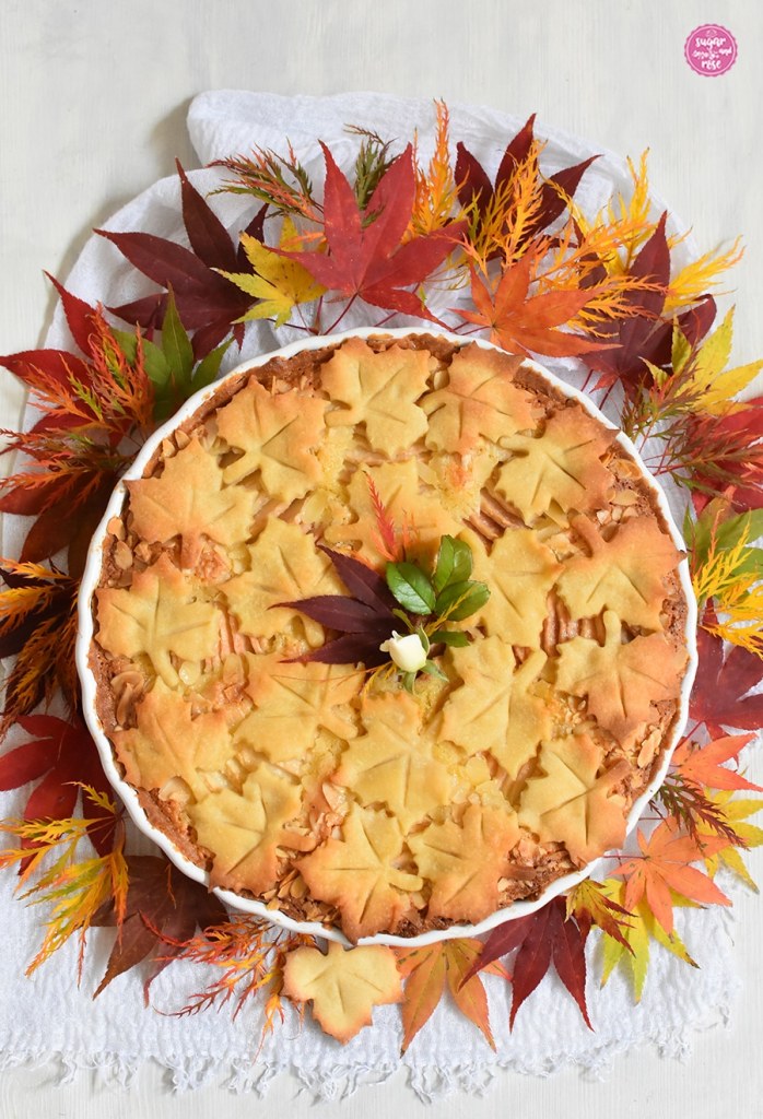 Rund um die Birnen-Mandeltarte liegen herbstlich gefärbte Ahornblätter, vom roten Blutahorn, zum gefiederten gelben Ahorn bis zum orangen Fächerahorn
