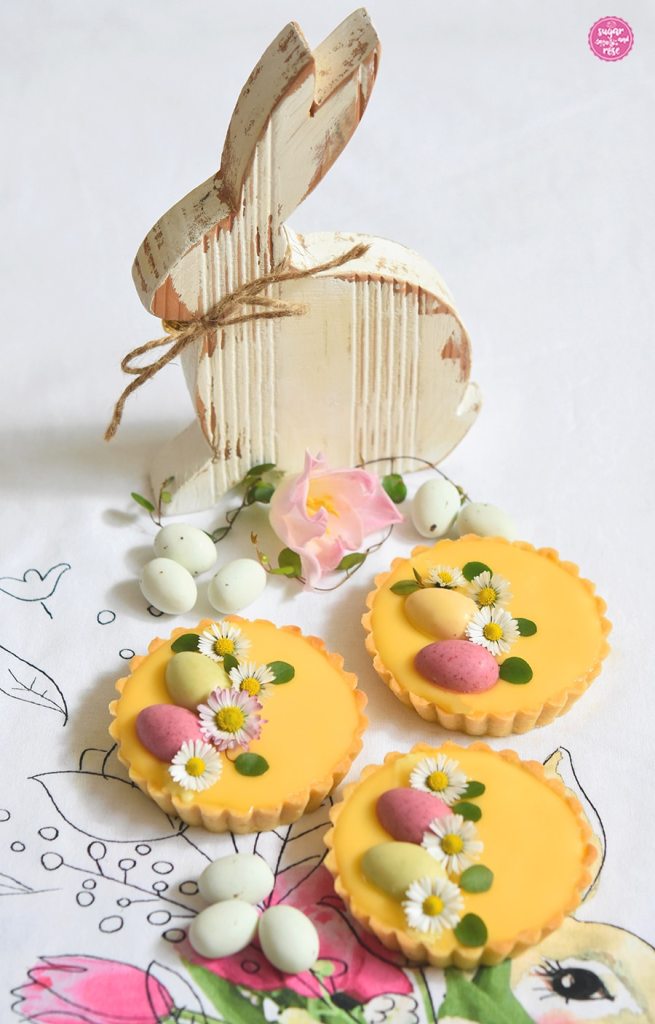 Eierlikör-Tartelettes vor einem weißen Holzhasen mit Wachteleiern als Deko
