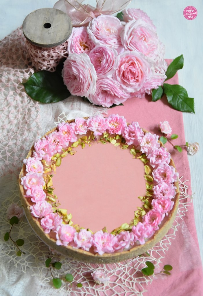 Rosen-Panna-cotta-Tarte dekoriert mit kleinen rosa Rosenblüten und grünen Pistazienkernen