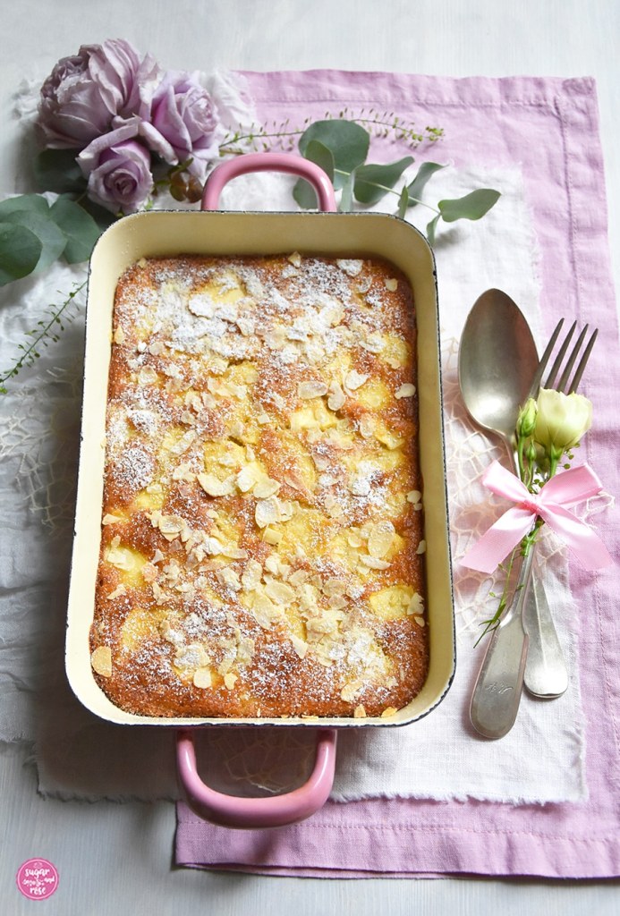 Apfelschedl gebacken in rosa Riess-Emaille-Pfanne (Rein), daneben altes Silberbesteck mit rosa Masche, alles auf rosa und weißer Stoffserviette